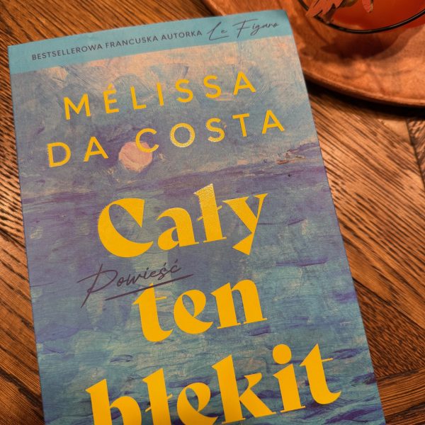 Okładka książki Melissy da Costy pt. "Cały ten błękit" (wersja polska). Tło okładki przedstawia niebieskie, malarskie pociągnięcia pędzlem imitujące wodę, z dużym żółtym tytułem na środku.